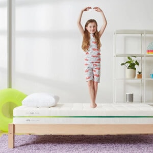 Child balancing on a bed in a bedroom.