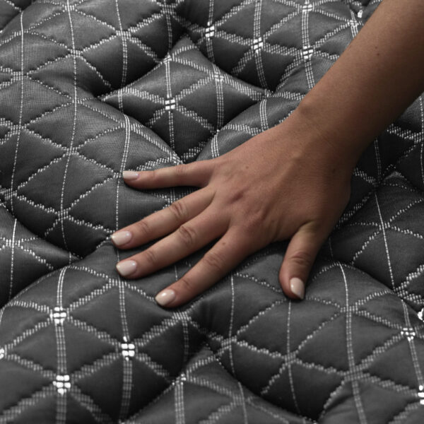 Hand pressing down on plush mattress surface.