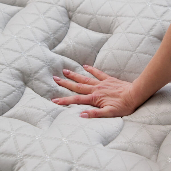 Hand pressing soft, quilted mattress surface.
