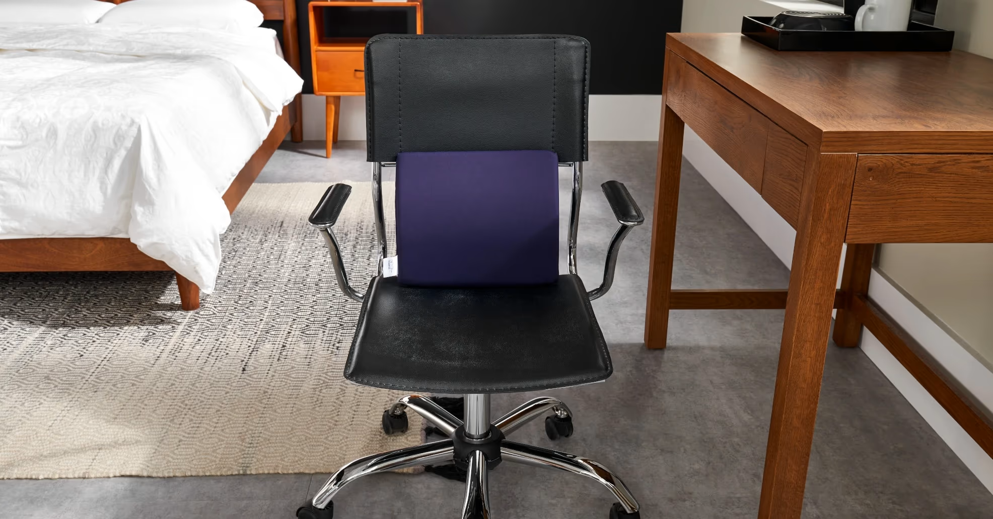 Office chair with lumbar support pillow in bedroom.