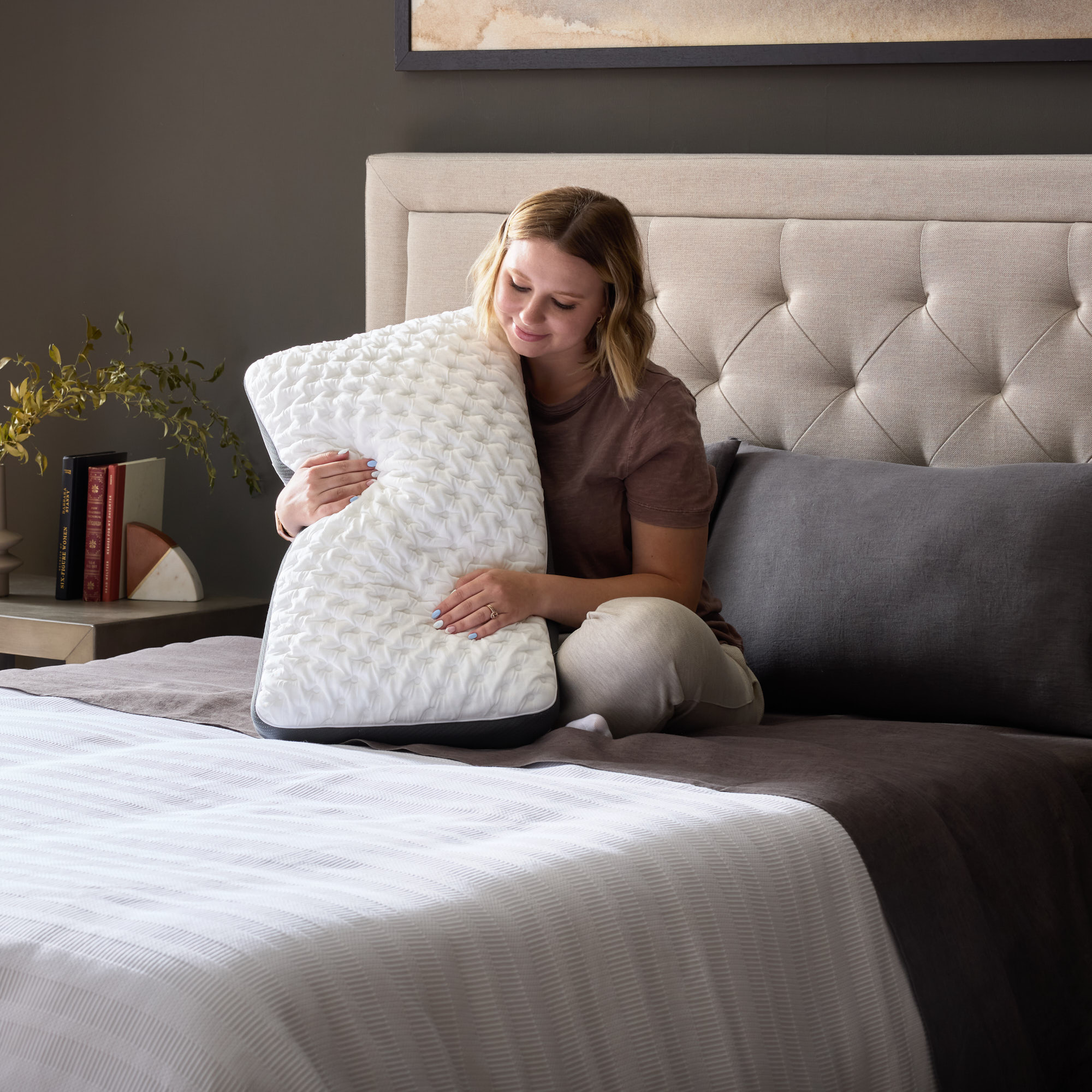 Woman embracing a textured white pillow on bed.